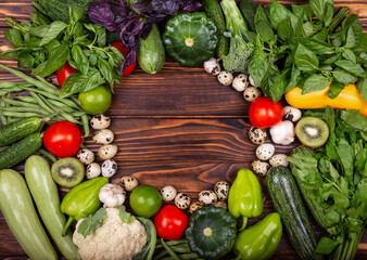 Empty vintage frame. Ripe vegetables. Frame of assorted fresh vegetables. Still Life. High angle of wooden cutting board surrounded by fresh herbs and assortment of raw vegetables on rustic wood table