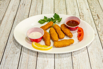 Chicken sticks battered with dipping sauces, parsley and lemon prepared in a Pakistani kebab restaurant