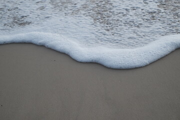 Soft wave of ocean on sandy beach. Nature background. Flat lay concept. Place for your text