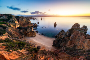 Sunrise at Camilo beach in Lagos, Algarve, Portugal. Wooden footbridge to the beach Praia do Camilo, Portugal. Picturesque view of Praia do Camilo beach in Lagos, Algarve region, Portugal.