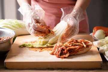 Woman making kimchi cabbage on wooden board, Popular homemade Korean traditional fermented side dish food - obrazy, fototapety, plakaty