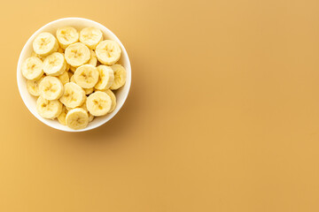 Many banana slices in white bowl. Top view