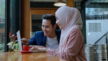 Smiley muslim teamwork use laptop in coffee shop