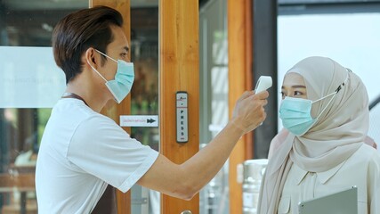 Staff uses infrared thermometer to measure fever at coffee shop.