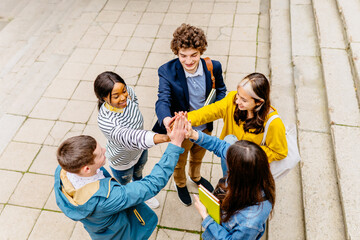 Concepts about friendship, teamwork, immigration and unity. Several people students friends of diverse ethnics hugging while standing in a circle, giving high five, smiling and looking at each other.