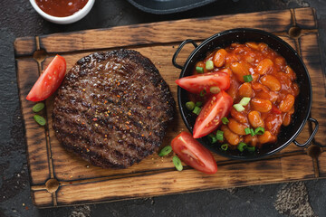 Rustic wooden serving tray with grilled balkan meat patty or pljeskavica and prebranac, view from above, horizontal shot