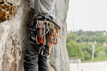 unrecognizable person climbing a vertical rock wall. detail of its harness with climbing hooks....