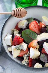 Closeup of summer salad with beetroot, fresh strawberry, gorgonzola and brie cheese, vertical shot, selective focus