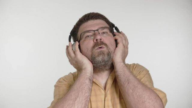 Portrait of bearded 48 years old caucasian man enjoy listen to fast rhythmic music by wireless silver headphones at home.