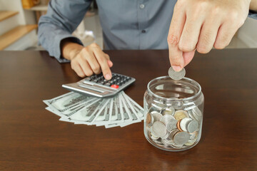 Investment and Saving money concept. businessman is putting conis in glass
