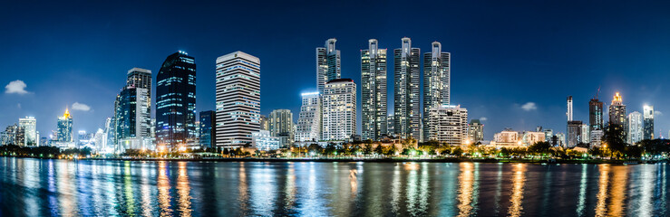 Fototapeta na wymiar Panorama Beautiful skyscrapers at night in a modern and civilized city.