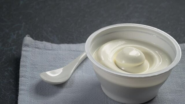 Bowl of cream cheese with spoon on blue napkin rotating