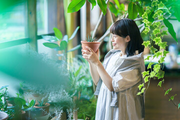 笑顔で観葉植物の様子を見る若い女性