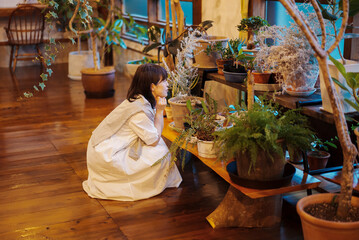 笑顔で観葉植物の様子を見る若い女性