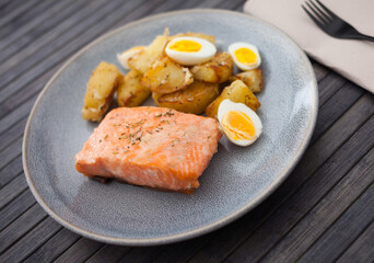 baked salmon fillet with fried potato wedges and quail eggs halves