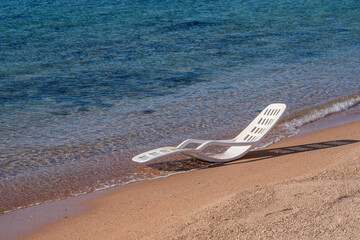 Fototapeta na wymiar White plastic sun lounger in sea water on a tropical beach in Sharm El Sheikh, Egypt