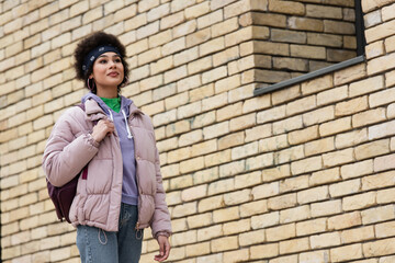 African american woman with backpack standing on street