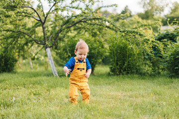 Happy baby outdoors, toddler walks in the summer garden