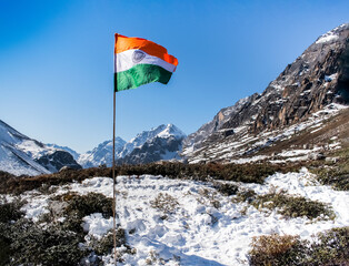 Indian National flag Tricolor or Tiranga waving high in the sky with snow covered mountains and blue sky in the background