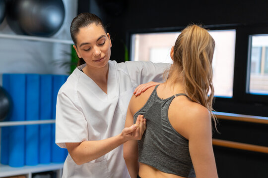 Physiotherapist fitting shoulder joint of woman