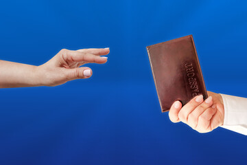 The hand reaches for the passport. The hand holds out a passport. The concept of obtaining...