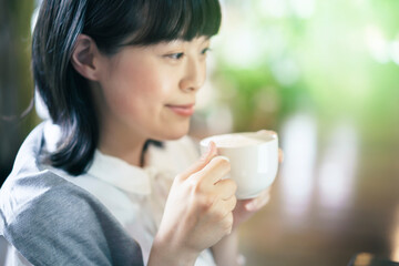 暖かい雰囲気の空間で、コーヒーを飲む若い女性