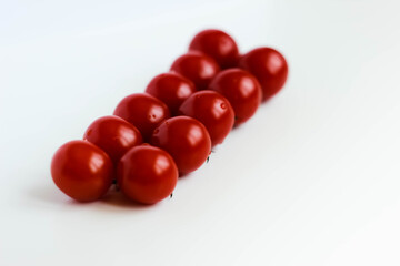 Fresh red delicious cherry tomatoes on white background. Summer agriculture. Italian cousine. Shallow depth of field selective focus creative image.