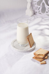 A glass of milk on a marble plate on a white table cloth and freshly baked cookies