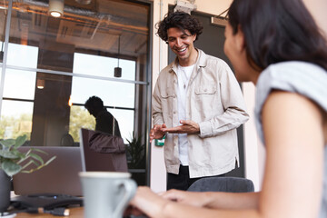 Young couple with laptops at desks preparing for online meeting in rented open plan office space