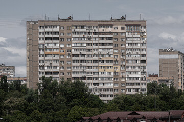 Facade of an overcrowded shabby apartment building of a multi-storey Soviet panel house, on a hot...