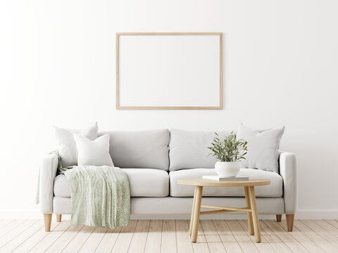 Horizontal poster mockup with wooden frame in living room interior with grey sofa, pillows, green throw, olive twigs in vase and coffee table on empty wall background. 3D rendering, illustration