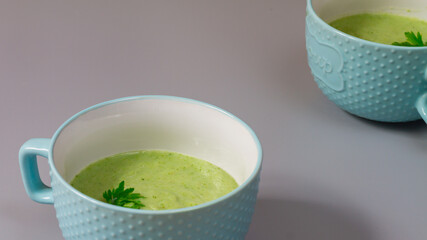 Green cabbage broccoli soup in plates decorated with parsley leaves