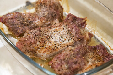 Pepper and spices on juicy fresh pieces of pork neck prepared for baking