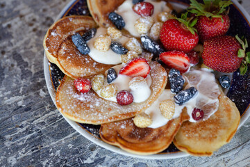 Pancakes with strawberries and honeysuckle with powdered sugar macro.
