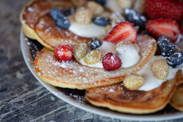 Pancakes with strawberries and honeysuckle with powdered sugar macro.