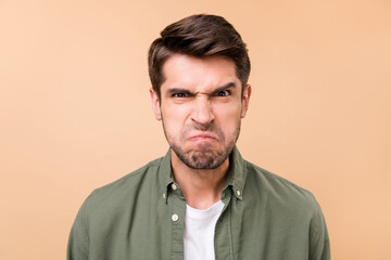 Photo of unhappy aggressive young man grimace face bad mood dislike isolated on pastel beige color...
