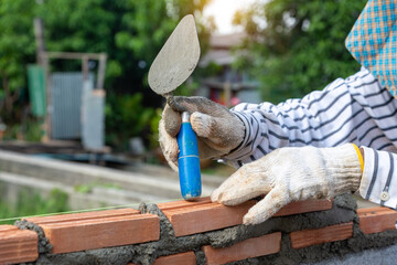 Masonry worker make concrete wall by cement block and plaster at construction site.