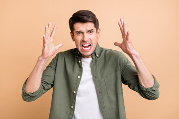 Photo of shocked aggressive young annoyed man raise hands bad mood isolated on beige color...