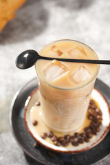 A glass with ice cubes and iced milk coffee on a white plate, view from above, close up