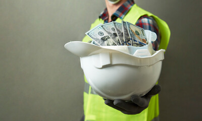 Construction worker with a hard hat full of dollar money