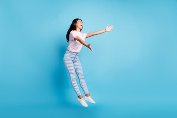 Full size photo of attractive young charming woman open hands empty space jump isolated on blue color background