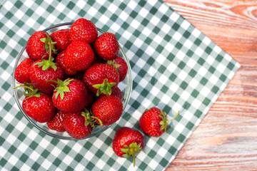 Fresh ripe strawberry in glass bowl on on a on a checkered napkin. Copy space. Close-up.