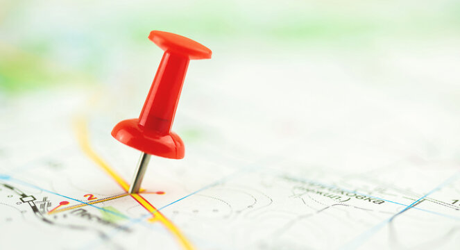 Close-up of a red push pin on the city map, selective focus composition photo