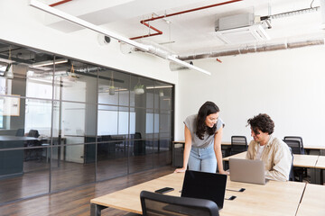Young couple renting work space for start up business having informal meeting in open plan office