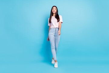 Fototapeta na wymiar Full length photo of cheerful nice young woman walk weekend good mood smile isolated on blue color background