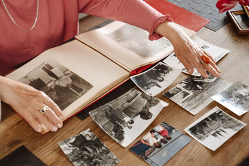 A close-up shooting of old photos in an album and female elderly hands