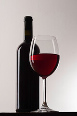 A bottle of red wine with a glass in front