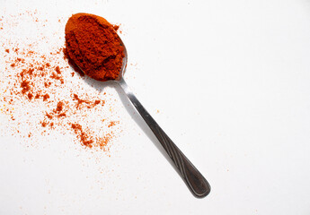 one spoonful with red seasoning. the seasoning is scattered on a white background
