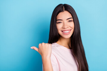 Photo of cheerful nice young woman point finger empty space thumb isolated on pastel blue color background