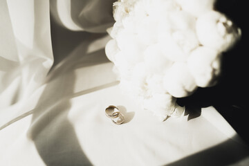 Beautiful toned picture with wedding rings against the background of a bouquet of flowers